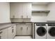 Bright laundry room with gray cabinetry, countertops, sink, and modern appliances, creating a clean and functional space at 5000 N Camelback Ridge Rd # 410, Scottsdale, AZ 85251