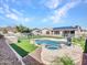 This backyard shows a pool with integrated spa and waterfall, surrounded by turf, and privacy fencing at 6603 W Via Dona Rd, Phoenix, AZ 85083