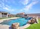 Backyard showcasing a sparkling blue pool with a rock waterfall and spa, complemented by lush artificial turf at 6603 W Via Dona Rd, Phoenix, AZ 85083