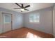 An empty room with hardwood floors, ceiling fan, a window with blinds and an exterior door to the backyard at 808 W 9Th St, Tempe, AZ 85281