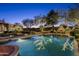 Sparkling pool with lush landscaping, outdoor fireplace and seating, and trees lit with decorative lights at 9820 E Thompson Peak Pkwy # 841, Scottsdale, AZ 85255