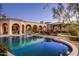 Beautiful swimming pool at dusk, surrounded by the well-lit home exterior and decorative landscaping at 9820 E Thompson Peak Pkwy # 841, Scottsdale, AZ 85255