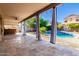 Spacious covered patio with stone flooring and ceiling fan overlooking the sparkling pool, an outdoor oasis for relaxing at 10452 E Florian Ave, Mesa, AZ 85208