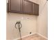 Functional laundry room featuring tile flooring, upper cabinets, and convenient utility connections for laundry appliances at 10452 E Florian Ave, Mesa, AZ 85208