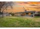 Expansive backyard showcasing a covered patio, fruit trees, and a well-kept lawn under a stunning sunset sky at 1109 E 8Th St, Mesa, AZ 85203