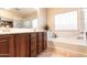 Bright bathroom features a soaking tub, wood cabinets, and large mirror at 11207 N 165Th Ave, Surprise, AZ 85388