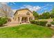 Exterior shot of a home and backyard featuring a covered patio, manicured lawn, and lush landscaping at 1165 E Erie St, Gilbert, AZ 85295