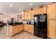 Stylish kitchen featuring natural wood cabinetry, black countertops, stainless steel appliances, and barstool seating at 1165 E Erie St, Gilbert, AZ 85295