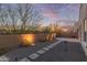 Serene backyard with desert landscaping, stone pathways, and privacy wall under a colorful evening sky at 13529 W Remuda Dr, Peoria, AZ 85383