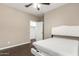 Cozy bedroom featuring a ceiling fan, dark wood floors, and a bright white headboard at 13529 W Remuda Dr, Peoria, AZ 85383