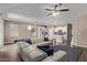 Open-concept living room with a large sectional sofa, tile flooring, ceiling fan, and seamless access to the kitchen at 13529 W Remuda Dr, Peoria, AZ 85383