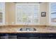 Close-up of the kitchen sink area, highlighting the granite countertops and window with plantation shutters at 15646 N 20Th Ave, Phoenix, AZ 85023