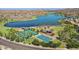 A scenic view from above showcases a lake, tennis and basketball courts, park, and nearby homes at 18601 W Thunderhill Pl, Goodyear, AZ 85338