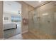 Primary bathroom featuring a modern glass shower with stone flooring and a bedroom view at 18601 W Thunderhill Pl, Goodyear, AZ 85338