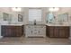 Well-lit bathroom boasting dual vanities with contrasting cabinets and a central storage unit at 18601 W Thunderhill Pl, Goodyear, AZ 85338