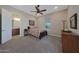 Bedroom with ceiling fan, soft carpet, and access to a bathroom at 18601 W Thunderhill Pl, Goodyear, AZ 85338