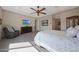 Bright bedroom featuring a large window, ceiling fan, TV and adjacent sitting area at 18601 W Thunderhill Pl, Goodyear, AZ 85338