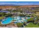 An aerial view of a beautiful community pool with palm trees, water slides and a mountain view at 18601 W Thunderhill Pl, Goodyear, AZ 85338