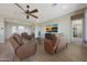 Inviting living room with hardwood floors, a ceiling fan, TV, and comfortable leather seating at 18601 W Thunderhill Pl, Goodyear, AZ 85338