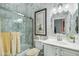 Well-lit bathroom with marble tiled walls, glass shower and vanity with white countertop at 2102 E Norwood St, Mesa, AZ 85213