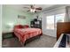 Neutral colored bedroom with a patterned bedspread, ceiling fan, and view out the window at 2562 E Oxford Ct, Gilbert, AZ 85295