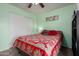 Cozy bedroom with red patterned bedspread, light-green painted walls, ceiling fan, and closet with sliding white doors at 2562 E Oxford Ct, Gilbert, AZ 85295