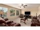 Cozy living room with carpet, large windows, ceiling fan, and comfortable leather sofas at 2708 E Desert Rose Trl, San Tan Valley, AZ 85143