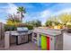 Outdoor kitchen area with a built-in grill, storage spaces, and a lush landscaped backyard at 2708 E Desert Rose Trl, San Tan Valley, AZ 85143