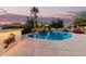 Beautiful pool area featuring lush landscaping, palm trees, rock waterfall and comfortable seating for entertaining at 2708 E Desert Rose Trl, San Tan Valley, AZ 85143