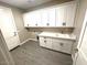 Laundry room featuring overhead cabinets, sink, and hardwood flooring at 2734 N Trevino Pl, Mesa, AZ 85215