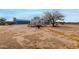 A large backyard with a bright blue house, camper, trees and dry, dirt yard at 30446 W Portland St, Buckeye, AZ 85396