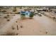 Aerial view of a blue single story house with a white door and a desert landscape with solar panels on the roof at 30446 W Portland St, Buckeye, AZ 85396