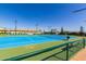 Bright blue and green tennis court on a sunny day with fencing, lighting, and community landscaping at 3117 S Signal Butte Rd # 501, Mesa, AZ 85212