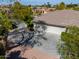 View of the home's garage and driveway nestled in a desert landscape with mature trees and landscaping at 3527 E Indigo Cir, Mesa, AZ 85213