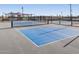 New blue and gray pickleball court in a community setting, with a black fence and recreational amenities at 37357 W San Clemente St, Maricopa, AZ 85138