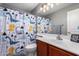 A kid-friendly bathroom features a blue and yellow dinosaur shower curtain and a light wood vanity at 3763 S Laurel Way, Chandler, AZ 85286