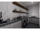 Well-organized laundry room with modern appliances, open shelving, and stylish countertop with black faucet at 42400 N Sierra Vista 2 Dr, Cave Creek, AZ 85331