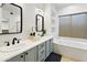 Bathroom featuring double sinks, light blue cabinets, and a separate tub with a window at 6348 W Hill Ln, Glendale, AZ 85310