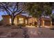 Beautiful home exterior featuring desert landscaping, a stone walkway, and mature trees under a twilight sky at 6576 E Whispering Mesquite Trl, Scottsdale, AZ 85266