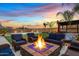 Backyard with a cozy fire pit surrounded by comfortable seating, lush lawn, and mature palm trees at 10713 E Tesla Ave, Mesa, AZ 85212