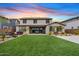 Expansive backyard featuring lush green lawn, covered patio, and manicured landscaping at twilight at 10713 E Tesla Ave, Mesa, AZ 85212
