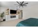 Bedroom featuring custom built-ins, an electric fireplace, floating shelves, and a ceiling fan at 10713 E Tesla Ave, Mesa, AZ 85212