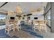 Bright clubhouse lounge area with stone fireplace, large windows, designer light fixtures, and comfortable table seating at 10713 E Tesla Ave, Mesa, AZ 85212