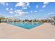 Community pool with a large pool deck, lounge chairs, umbrellas, and shade structures at 10713 E Tesla Ave, Mesa, AZ 85212
