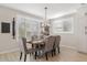 Dining room with six tufted chairs and a rustic chandelier, illuminated by a large window at 10713 E Tesla Ave, Mesa, AZ 85212