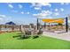 Outdoor fire pit with seating area, artificial turf, and an outdoor kitchen with covered seating at 10713 E Tesla Ave, Mesa, AZ 85212