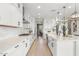 Bright kitchen features white cabinets, quartz countertops, stainless appliances, and wood-look tile flooring at 10713 E Tesla Ave, Mesa, AZ 85212