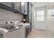 Modern laundry room with front loading washer and dryer and shaker cabinets at 10713 E Tesla Ave, Mesa, AZ 85212