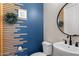 Stylish powder room featuring a navy blue wall, modern sink and toilet, complemented by unique decorative accents at 10713 E Tesla Ave, Mesa, AZ 85212
