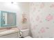 Charming powder room with floral wallpaper, decorative mirror, and neutral countertop sink at 10844 N 37Th St, Phoenix, AZ 85028